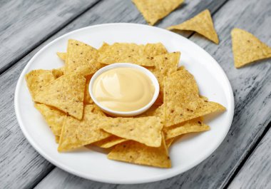 Tahta masa zemininde üçgen şekilli mısır tortilla cipsi ve sos, yakın görüş. 