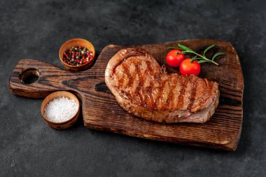 Baharatlı ızgara biftek, arka planda kesim tahtası.