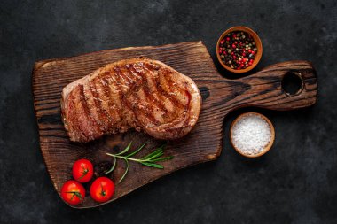 Baharatlı ızgara biftek, arka planda kesim tahtası.