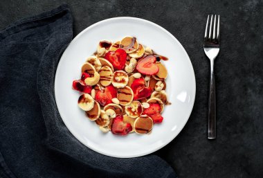 Çilekli mini krepler, muzlar, arka planda bir tabakta fındıklar. Metnin için kopyalama alanı olan lezzetli kahvaltı kavramı