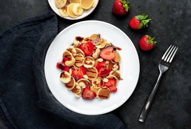 Çilekli mini krepler, muzlar, arka planda bir tabakta fındıklar. Metnin için kopyalama alanı olan lezzetli kahvaltı kavramı