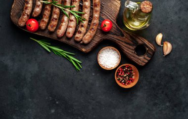 Tahtada ızgara sosis, sarımsak, biberiye, domates, zeytinyağı şişesi, barbekü konsepti.