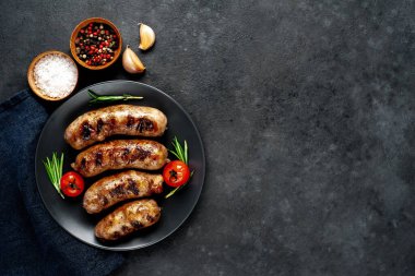 Metnin için fotokopi alanı olan taştan bir arka planda tabaktaki malzemelerle ızgara sosisler.