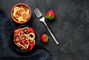 Çilekli mini krepler, muzlar, arka planda bir tabakta fındıklar. Metnin için kopyalama alanı olan lezzetli kahvaltı kavramı