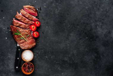 Baharatlı ızgara biftek ve arka planda bir bıçak.