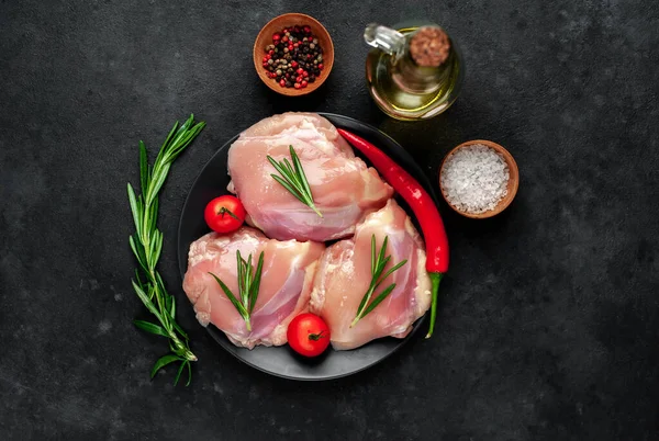 raw chicken thighs on plate with tomatoes and spices , close view