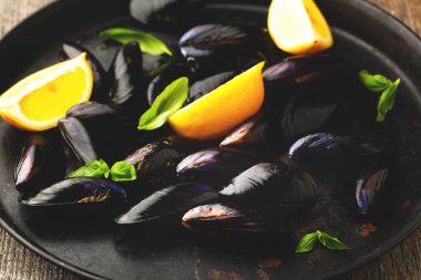 Limonlu çiğ midye ve ahşap bir sırtüstü tabakta otlar.