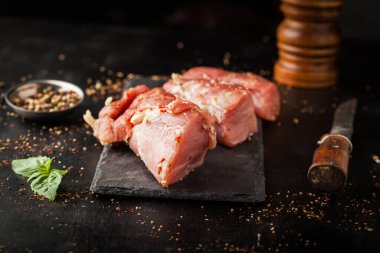 Salamurada taze çiğ fileto. Koyu bir grupta baharatlar.