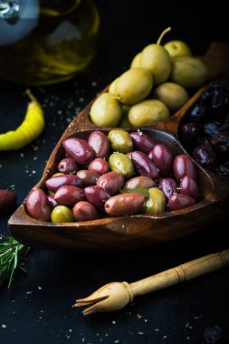 Çeşit çeşit salamura zeytinli, otlu ve biberiyeli, koyu arkaplanda.