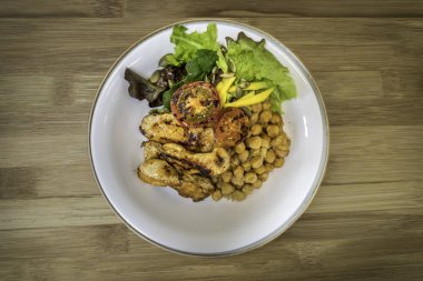 Ahşap zemin üzerinde nohut ve salata ile ızgara tavuk