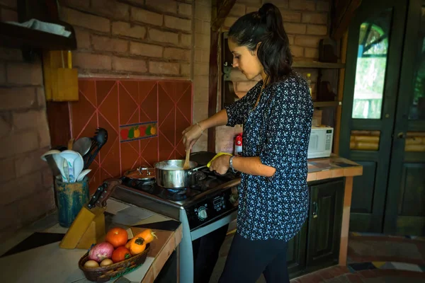 Young woman cooking in an outdoor kitchen, common in houses of temperate climates — Stock Photo, Image