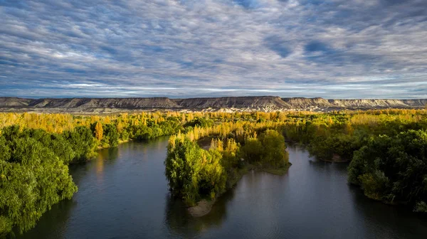 Landscape of a valley in autumn. There is a huge river and big mountain cliff behind