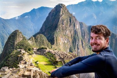 Machu Picchu 'da poz veren bir adam. Machu Picchu kalesinin kalıntılarını görebilirsiniz.
