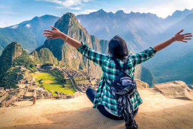 Machu Picchu 'nun muhteşem manzarasını kolları açık hayal eden bir kadın turist.