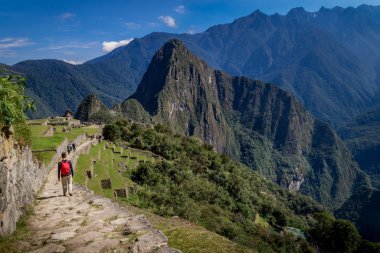 İnka patikasında yürüyen adam, Huayna Picchu dağları arkasında.