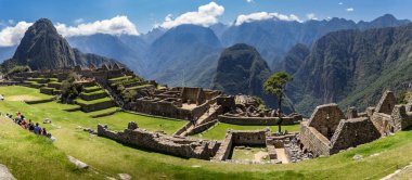 Machu Picchu kalesinin panoramik manzarası içeriden. Arkasında yeşil bitkilerle dolu büyük ve güzel dağları takdir edebiliriz..