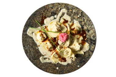 Beyaz soslu Tortellini makarnası beyaz arka planda pembe çiçekli mermer bir tabakta servis ediliyor.. 