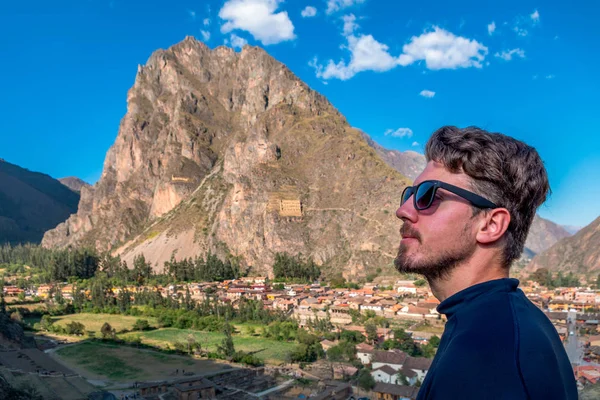 Un turista de perfil con gafas de sol, con el fondo de la ciudad de Ollantaytambo, Valle Sagrado de los Incas . — Foto de Stock