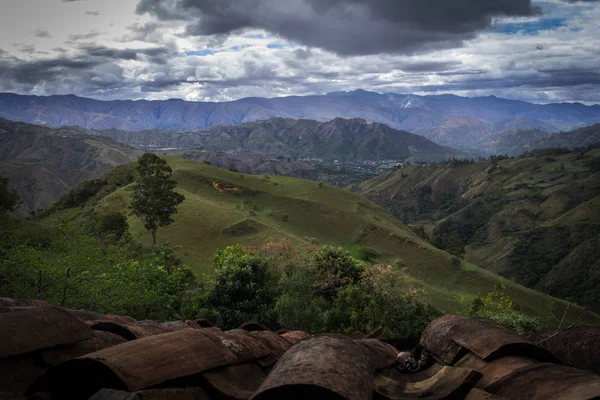 Vista panoramica della sierra ecuadoriana dal tetto di una casa. Ci sono grandi nuvole, montagne, arbusti e alberi — Foto Stock