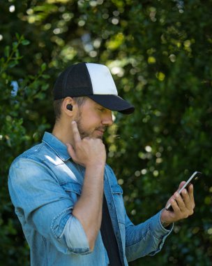 Kablosuz kulaklıkları ve cep telefonuyla müzik dinleyen beyaz bir adam. Teknolojik konsept