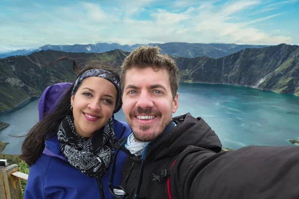 Multi- ethnic travel couple taking a selfie at Quilotoa, lake inside a volcano carter in Ecuador, South America