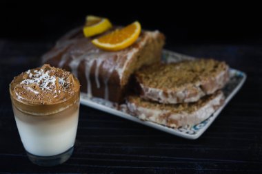 Bir bardak Dalgona kahvesi ve portakallı kek. Son moda kremalı kahve. Siyah arkaplan