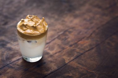 Bardakta servis edilen buzlu Dalgona kahvesi. Moda kremalı kremalı kahve. Ahşap kırsal arka plan