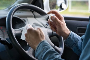 Adam direksiyonu mendil ve dezenfektanla temizliyor. Covid-19 veya Corona virüsü konsepti. Kapat.