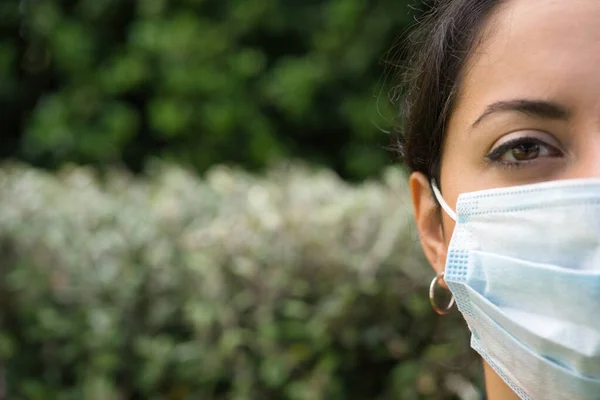 Face of a woman wearing face mask looking sad in outdoor background. Copy space. Covid-19 concept