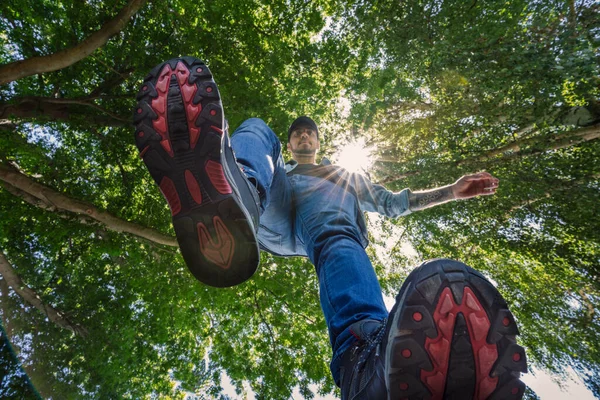 Male foot stepping on camera, floating effect. Outdoor background surrounded by trees
