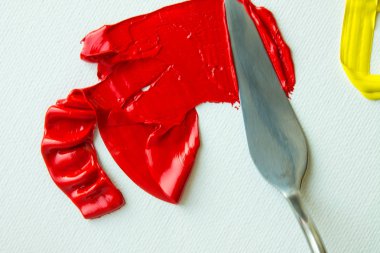 Beyaz bir palette kırmızı ve sarı yağlı boya karışımı.