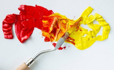 Beyaz bir palette kırmızı ve sarı yağlı boya karışımı.