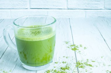 Japon yeşil çayı Şeffaf cam bardakta Matcha Tuğla duvara karşı beyaz ahşap bir masaya yakın