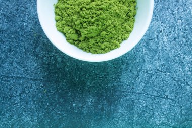 Beyaz porselen bir fincanda kurutulmuş yeşil Japon çayı. Gri desenli arka plana yakın, kopyalamak için alanı var.