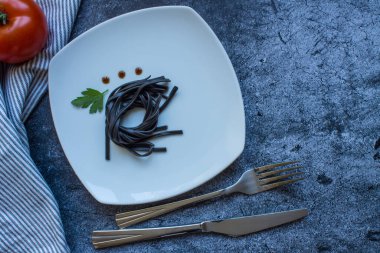 Beyaz kare tabakta mürekkep balığı mürekkebi ve maydanoz yaprağı ve gri desenli arka planda fotokopi alanı olan sos damlaları. Minimalizm