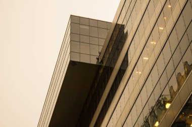 Çağdaş cam gökdelenin dış cephesinin bir parçası yansımaları ve arka planda bir fener fotokopi alanı olan bulutlu bir gökyüzünün.