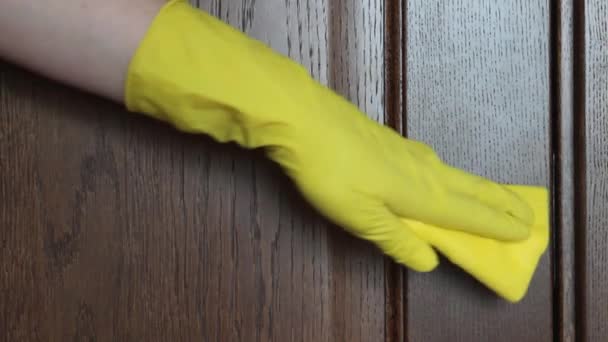一个女人的手戴着一只黄色的橡胶手套 在一个棕色木门的背景下 近距离擦拭门把手 停止结肠病毒 — 图库视频影像