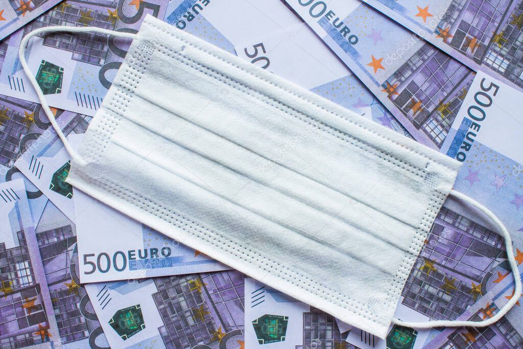 Medical disposable mask, body thermometer and tablets in a blister on 500 Euro paper banknotes. Concept: speculation on the medication during the outbreak of coronavirus