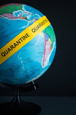 Üzerinde yazı olan dünya, siyah arka planda sarı şeritli bir karantina alanı. Kavram durdurma koronavirüsü.