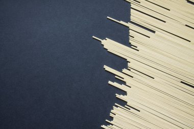 Fotokopi alanı olan siyah bir zemine saçılmış çiğ spagetti.