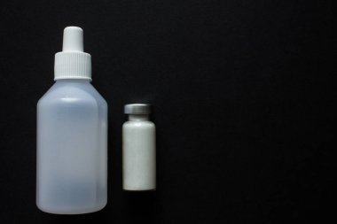 Beyaz ilaç ve plastik şişeli cam ampul. Siyah arkaplanı fotokopi alanı görünümlü.