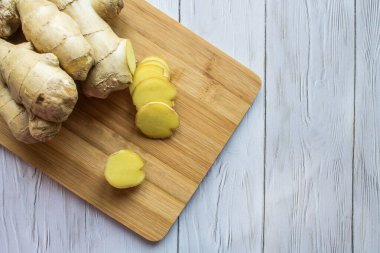 Zencefil kökü, ahşap mutfak tahtasındaki dilimlenmiş dilimlerle yakın çekim yap.