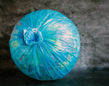 Plastik bir çöp torbasında, gri desenli arka planda yakın plan bir dünya. Kavram: Doğanın korunması, dünyadaki çevre sorunları.