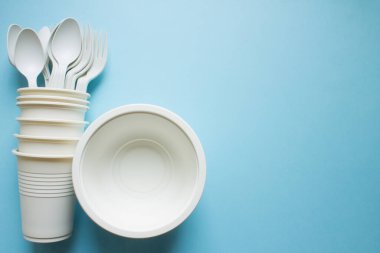 Biyolojik ayrıştırılabilir masa takımı: mavi arka plan yakın çekim alanı üzerinde çatallı tabaklar, bardaklar ve kaşıklar. Eğilim: ekoloji.