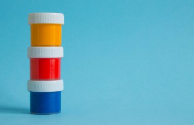 Çok renkli gouache boyalı plastik kavanozlar mavi arkaplanı kapatır ve boşluğu kopyalarlar