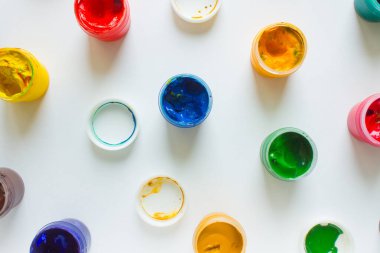 Beyaz kağıttan arka plan görünümlü çok renkli boya-plastik kavanozlar.