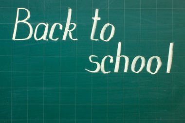 Yeşil bir karatahtaya beyaz tebeşirle yazı yazmak - okula yakın plan dön ve boşluğu kopyala.