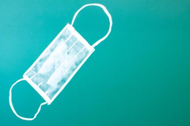 Yeşil bir karatahtaya tebeşir çizimi - beyaz tıbbi maske yakın plan ve boşluğu kopyala