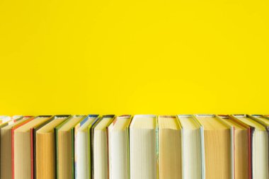 Parlak sarı arkaplanı kaplayan ve boşluğu kopyalayan düz bir kitap sırası