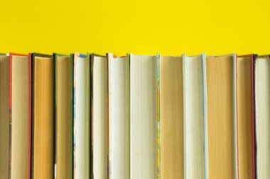 Parlak sarı arkaplanı kaplayan ve boşluğu kopyalayan düz bir kitap sırası